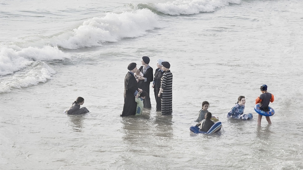 La ropa les impide adentrase en el mar, por eso la mayoría se queda en la orilla charlando.