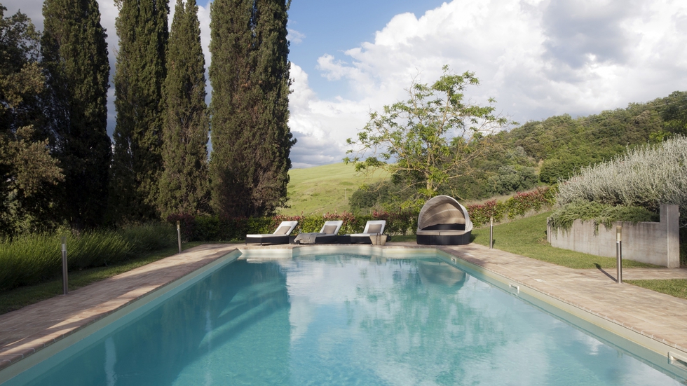 La piscina está situada en la parte trasera de la finca, junto a su frondoso jardín. Las tumbonas son de ratán, y la cama redonda con capota, de Kettal.